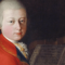 Portrait of Wolfgang Amadeus Mozart aged 13, in white wig, looking over his right shoulder, wearing red coat; music manuscript and string instrument in background.